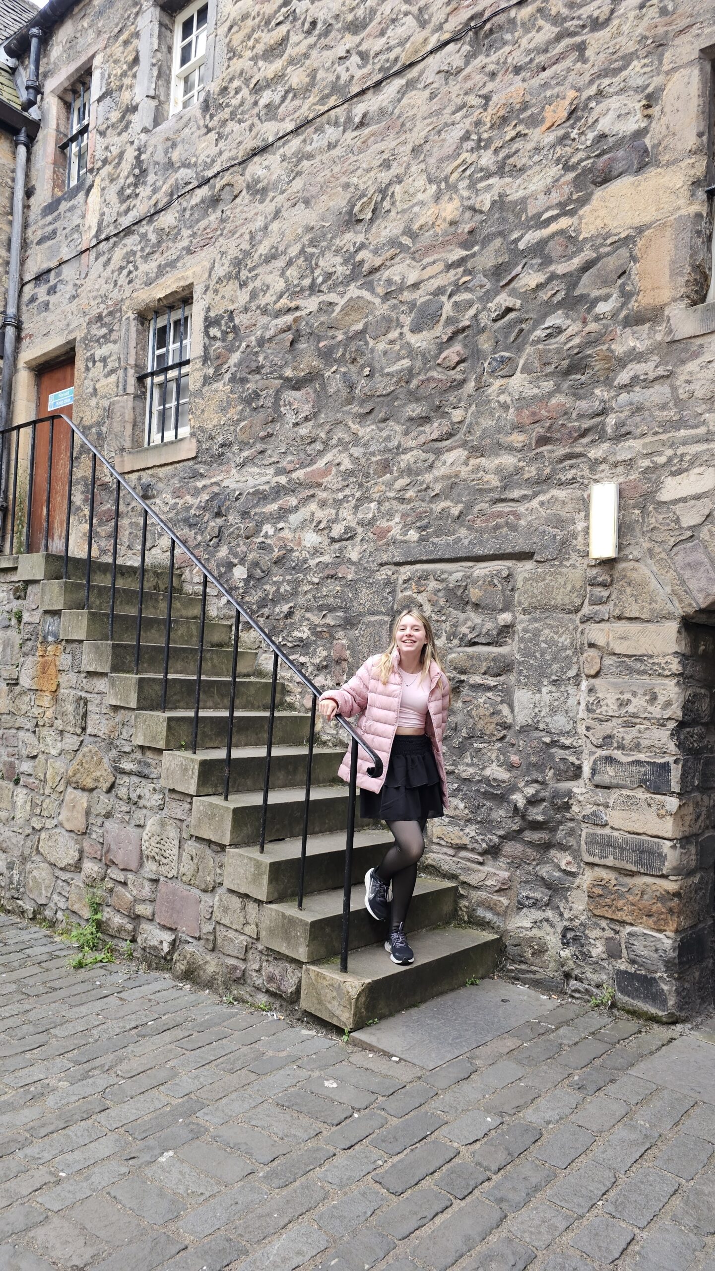Viela histórica Bakehouse Close em Edimburgo, com paredes de pedra escura e ambientação medieval usada como cenário de Outlander