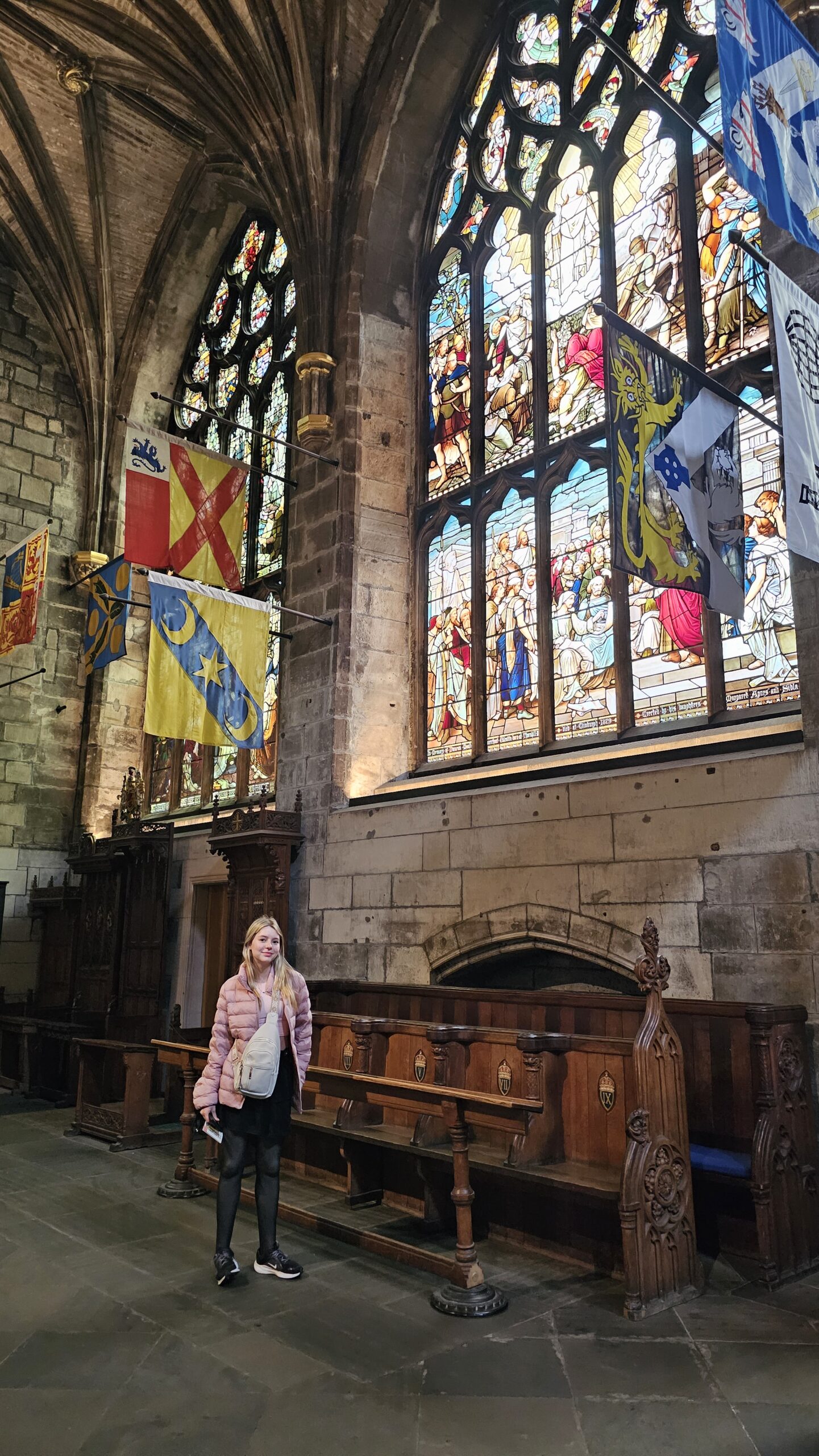Interior gótico da Catedral de St Giles em Edimburgo com vitrais coloridos e arcos.