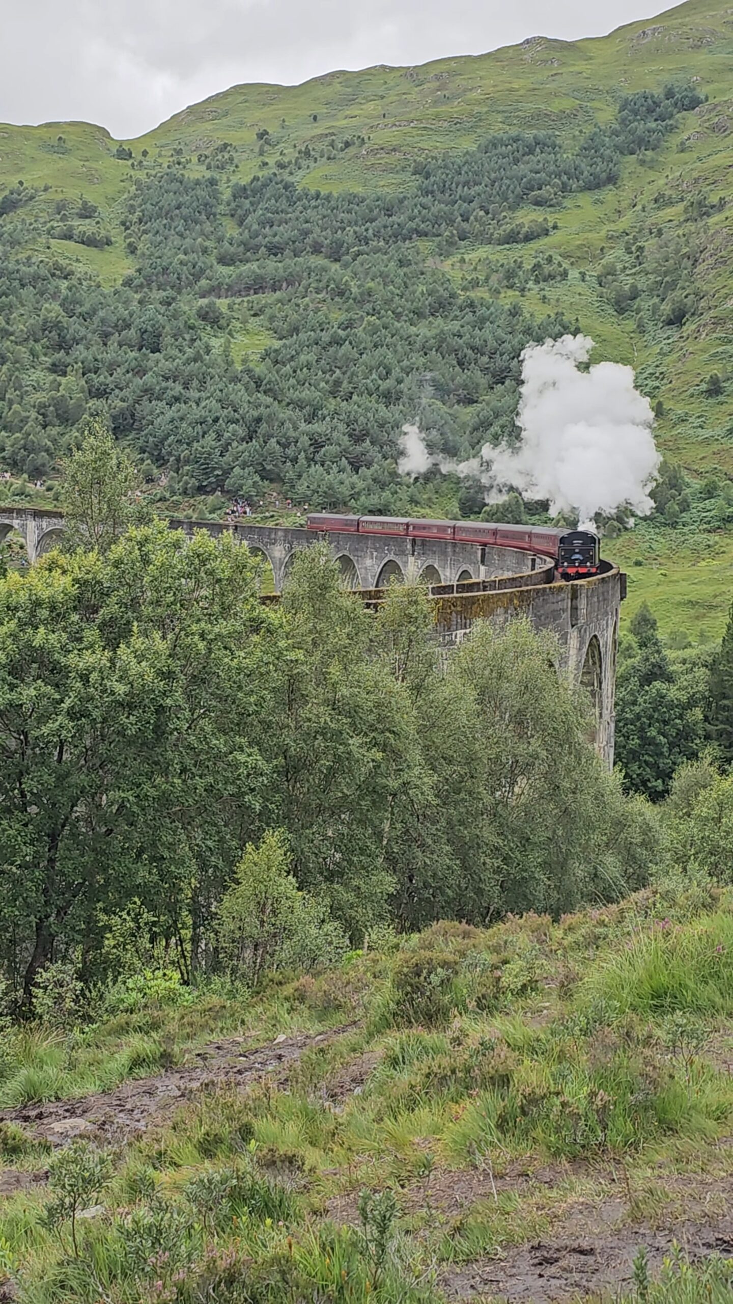 Trem a vapor Jacobite Steam Train (Expresso de Hogwarts) atravessando o Viaduto de Glenfinnan nas Highlands escocesas.