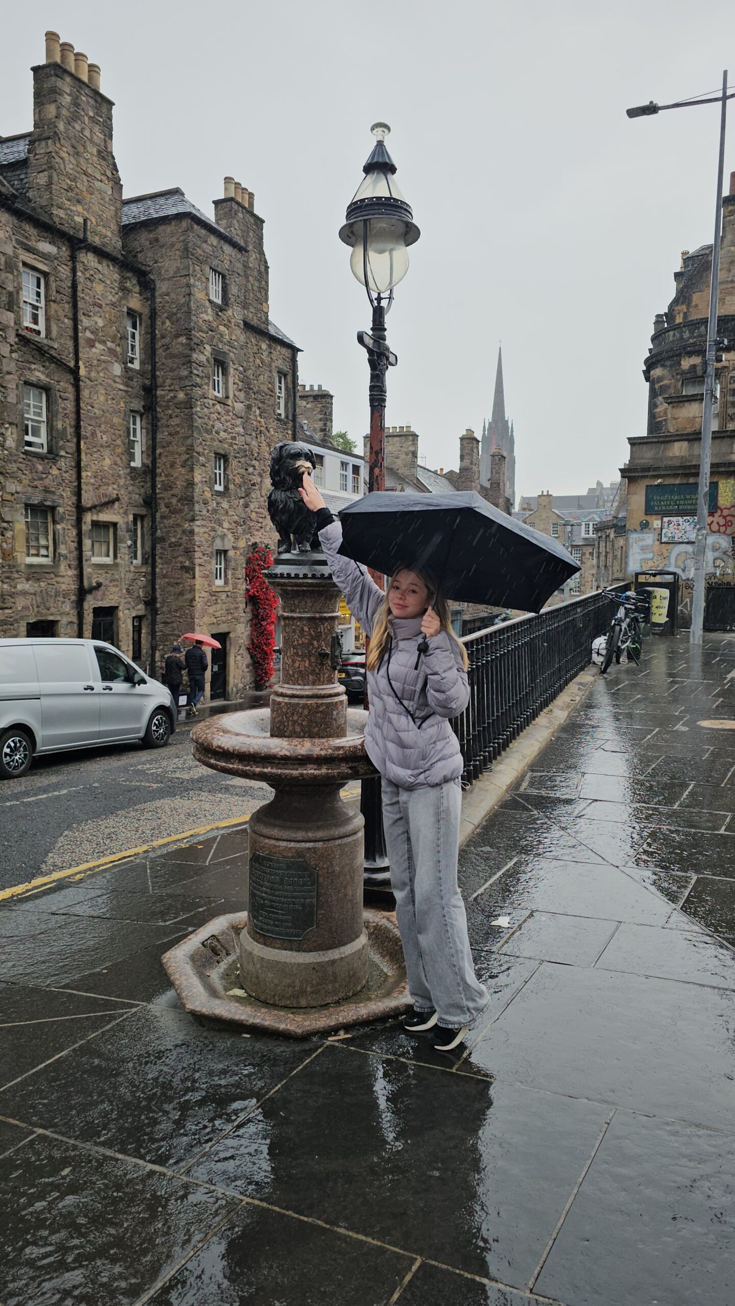 Estátua de bronze do Greyfriars Bobby em Edimburgo, com visitantes tocando seu nariz descascado pela prática turística.