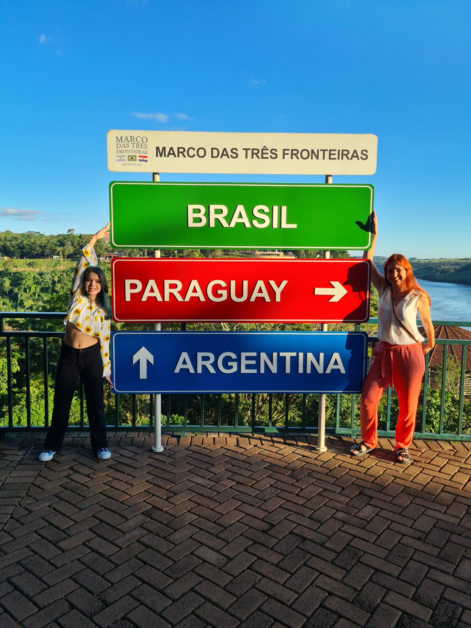 O que fazer em Foz do Iguaçu. Obelisco verde e amarelo do Marco das Três Fronteiras em Foz do Iguaçu, com vista para o encontro dos rios Iguaçu e Paraná