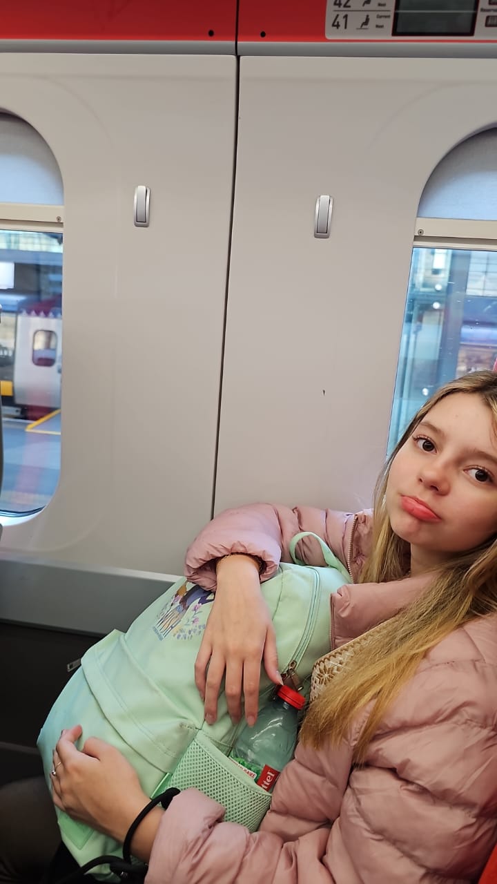 Anna Clara no espaço entre os vagões do trem LNER, onde as janelas são maiores, ao lado da placa dos assentos 41 e 42